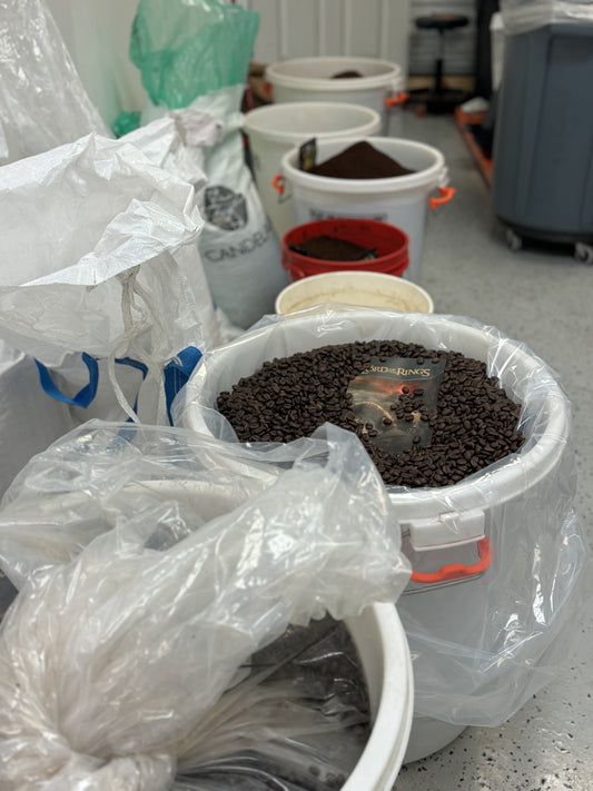 row of large bins filled with fresh roasted coffee beans and ground coffee